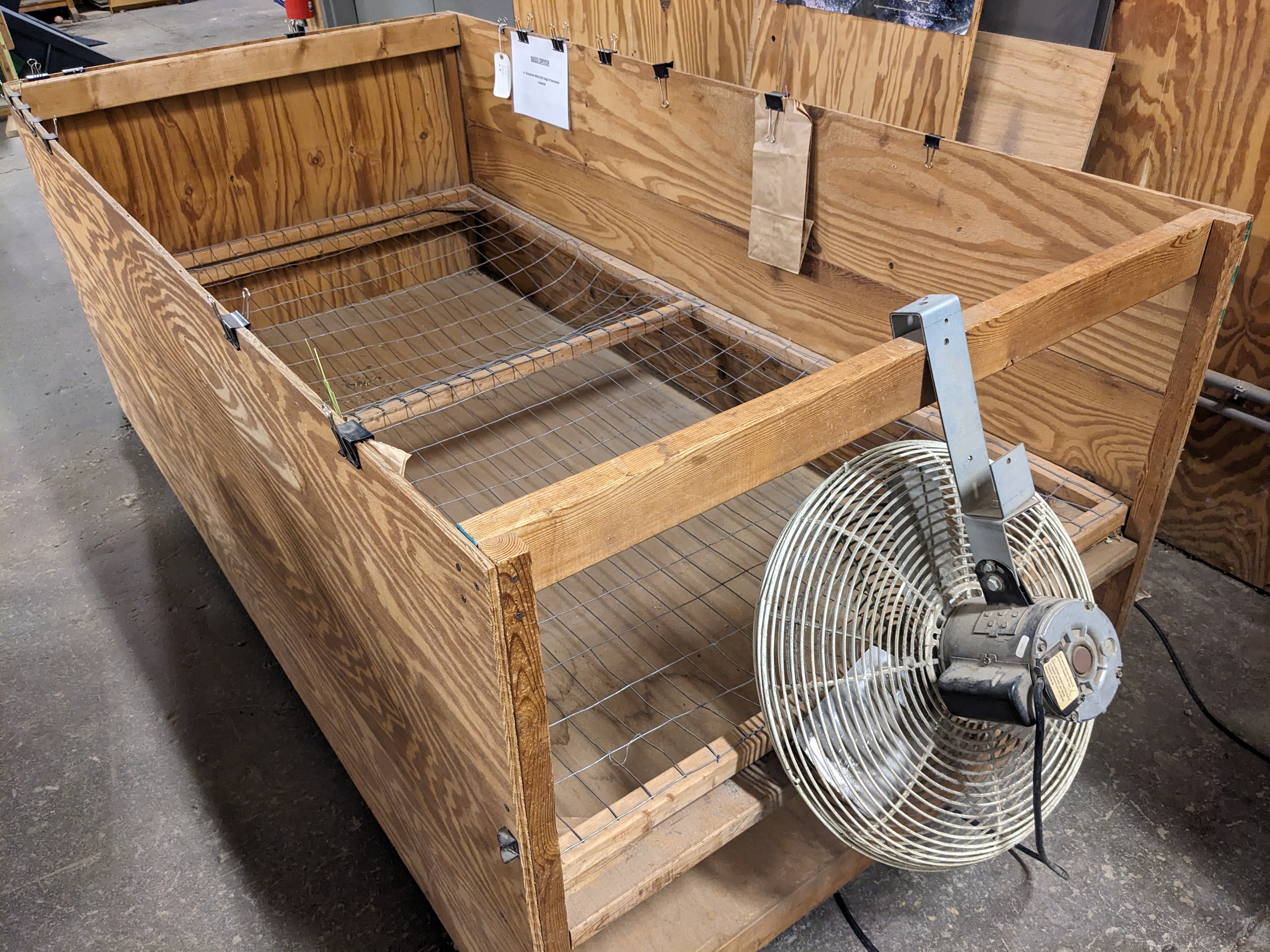 A wooden box with wire mesh bottom and fan for drying seed